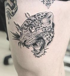 a black and white tattoo of a leopard on the thigh