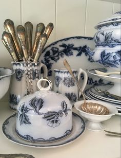 a table topped with plates and silverware next to a vase filled with gold spoons