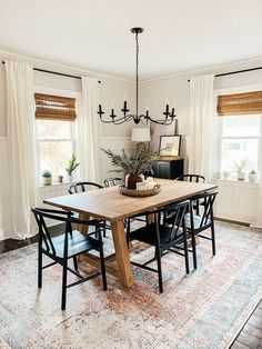 a dining room table with chairs and a rug on the floor in front of it