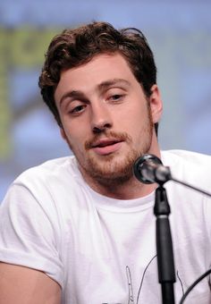 a man sitting in front of a microphone with his eyes closed and looking at the camera