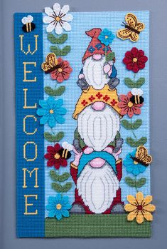 a cross - stitch card with an image of a gnome and flowers on the front