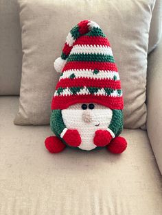 a crocheted snowman sitting on top of a couch next to a pillow