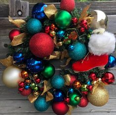 a wreath with christmas ornaments hanging from it's sides and a santa hat on top