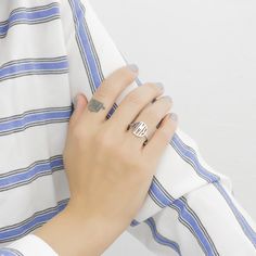 a woman's hand with a ring on top of her arm, wearing a striped shirt