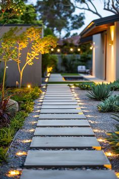 an outdoor walkway lit up with lights in the middle of it and surrounded by greenery