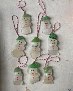 snowman ornaments are hanging from red and white twine