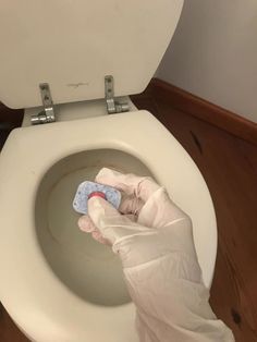 a person in white gloves cleaning a toilet