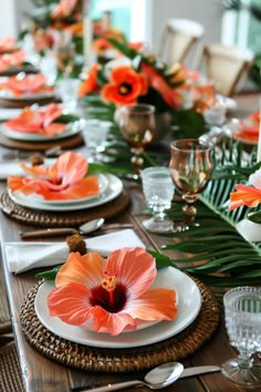 the table is set with orange flowers and place settings