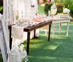 an outdoor wedding setup with white linens and flowers on the table, along with other decorations