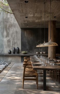 an outdoor dining area with wooden tables and chairs in front of a concrete wall, surrounded by stone steps