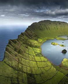 an aerial view of some water and land with mountains in the background on a cloudy day