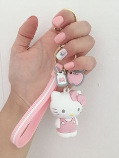 a hand holding a hello kitty keychain with pink and white designs on it