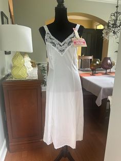 A white dress slip with lace trim.  Lace trim on the neckline and lace straps, which are non adjustable. In good vintage condition with no rips or stains.  This slips is shown on a size 6 dress form with a 26 inch waist and 34 inch bust - and it fits well. The bust measures 16 inches across from armpit to armpit laying flat, with extra room in the cups, and the fabric stretches. 41 inches from shoulder to hem. Please examine the pics, feel free to ask questions.  Size 27.  100% Nylon White Lace Slip Dress With Lace Patchwork, White Lace Slip Dress With Spaghetti Straps, White Sheer Camisole Slip Dress, Lace Trim Camisole Slip Dress For Daywear, White Lace Nightgown With Lace Trim, White Delicate Lace Camisole Slip Dress, Camisole Slip Dress With Lace Trim For Daywear, White Sleeveless Slip Dress With Delicate Lace, White Lace Sleeveless Slip Dress