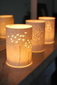 three lit candles sitting on top of a table next to each other with flowers painted on them