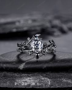 a white diamond ring sitting on top of a rock