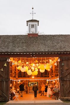 people are walking into a barn decorated with lights