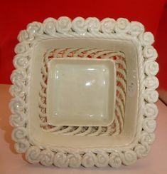 three white square dishes sitting on top of a table with red wall in the background