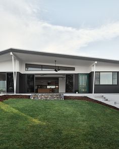 a modern house with grass and rocks in the front yard