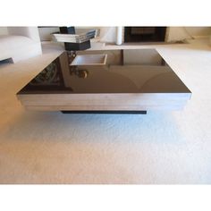 a black and silver coffee table on carpeted floor with white furniture in the background