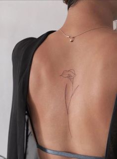 the back of a woman's body with a flower tattoo on her left shoulder