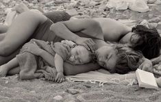 black and white photograph of two women laying on the beach with a baby in her lap