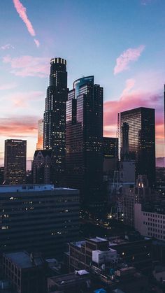 the city skyline is lit up at night, with skyscrapers in the foreground