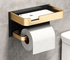 a gold and black toilet paper holder next to a white toilet