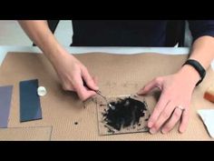 a person is cutting up some black paint on a piece of cardboard with scissors and glue