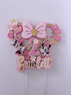 a cake topper with minnie mouse on it and the number two in pink, gold and white