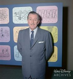 a man in a suit and tie standing next to a wall with cartoon drawings on it