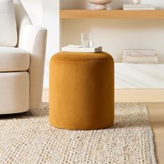 an orange ottoman sitting on top of a rug next to a white chair and table