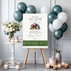 a football themed party sign in front of balloons and flowers with candles on the table