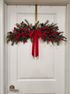 a white door with a red bow and evergreen wreath on it's front door