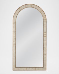 the arched mirror is made out of wood and has a white marble border around it