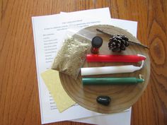 a wooden plate topped with different types of items on top of paper and glue next to a pine cone