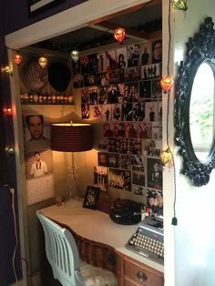 a desk and chair in a room with pictures on the wall above it, along with an old typewriter