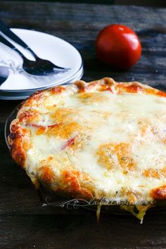 a pizza sitting on top of a wooden table next to a fork and spoons