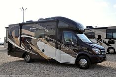 an rv parked in gravel next to two other motorhomes and one is black