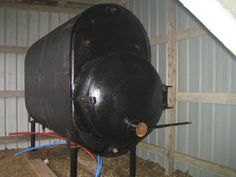 a large black tank sitting on top of a wooden floor next to a building with metal pipes