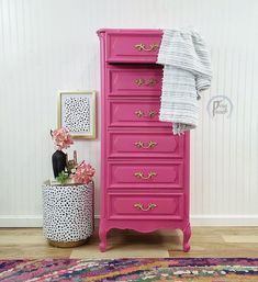 a pink chest of drawers next to a white wall and rug with flowers on it