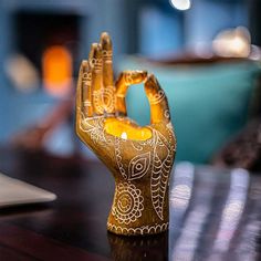 a small hand holding a candle on top of a wooden table next to a laptop computer