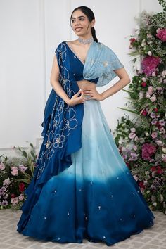 Blue ombre attached cancan lehenga with placement embroidery. Paired with a wrap style floral embroidered blouse and cape with floral embroidery. Components: 3 Pattern: Embroidery Type Of Work: Floral Neckline: V Neck Sleeve Type: Short Sleeves Fabric: Cape and Lehenga: Organza Satin, Blouse: Crepe Color: Blue Other Details:  Attached inner lining Lehenga: Length: 45 inches Attached cancan Blouse: Length: 14 Padded Note: All the jewellery worn by the model is not for sale Occasion: Sangeet - Aza Blue Cape, Wedding Lehenga Designs