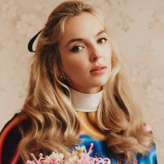 a woman with long blonde hair holding flowers