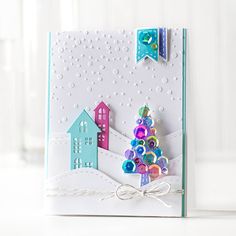 a handmade christmas card with a house and tree on the front, decorated with buttons