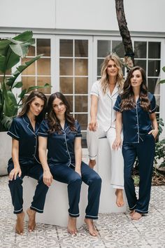 three women in matching pajamas posing for the camera with their feet up on a bench