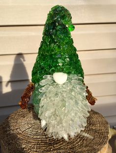 a glass santa clause sitting on top of a tree stump