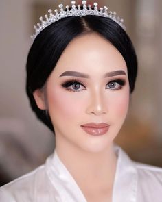 a woman wearing a tiara with pearls on it's head and dark hair