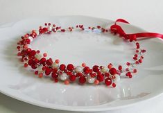 a white plate topped with a red and white beaded necklace on top of a table