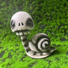 a small statue of a snail on some grass