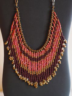 This necklace is made of gold, pink, brown and crystal seed beads. The strands are separated by small brass disks.  It is finished with a bronze chain and toggle closure.  I can adjust the length of the chain if you wish. Bohemian Gold Bib Necklace With Colorful Beads, Artisan Gold Beaded Necklaces With Dangling Beads, Gold Bohemian Beaded Necklace With Dangling Beads, Bohemian Gold Beaded Necklace With Dangling Beads, Bohemian Pink Necklace With Polished Beads, Unique Gold Beaded Crystal Necklaces, Unique Gold Beaded Crystal Necklace, Bohemian Gold Bib Necklace With Round Beads, Gold Beaded Necklace With Faceted Metal Beads